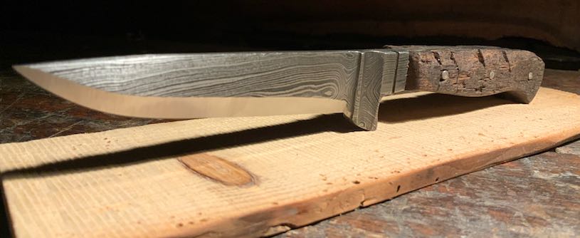 Damastmesser mit rustikalem Griff aus altem Eichenholz auf Holzbrett