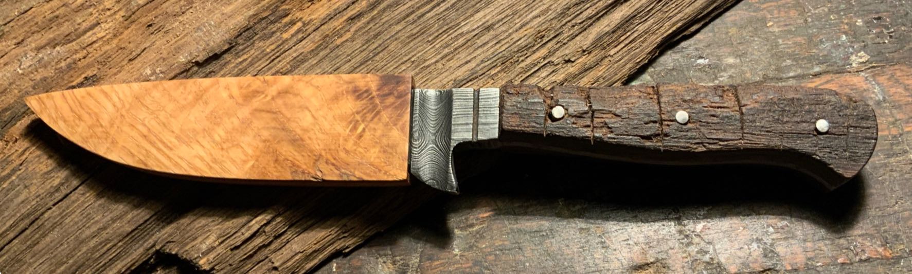 Damastmesser mit Griff aus altem rissigen Eichenholz und Scheide aus Kirsch-Holz auf Holztisch