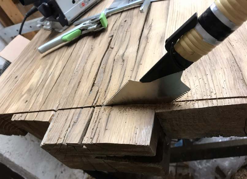 Handsäge beim Kürzen einer Altholz-Tischplatte