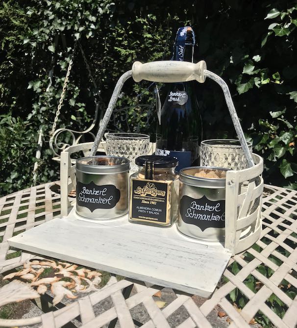 Weißer Holzkorb auf Gartentisch mit Snacks/Aperitif