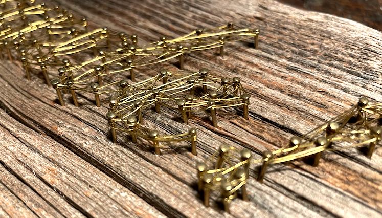 Detail Faden-Bild aus Messingdraht auf verwittertem Holz