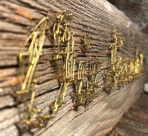 Detail Faden-Bild aus Messingdraht auf verwittertem Holz