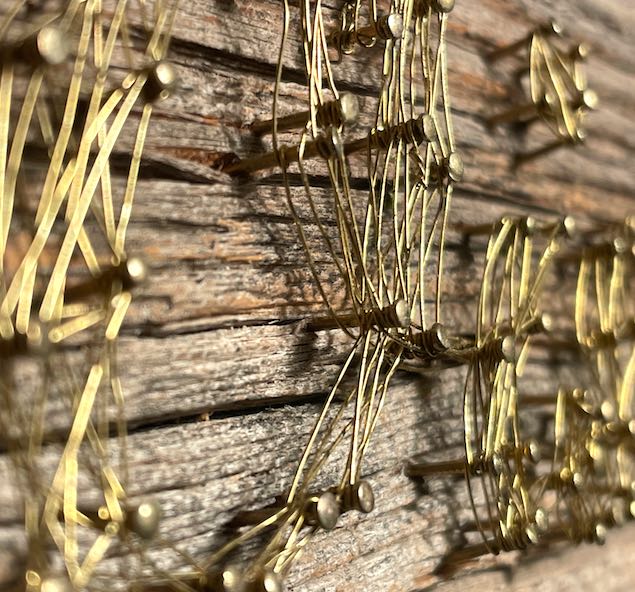 Close-up Faden-Bild aus Messingnägeln und -draht auf verwittertem Holz