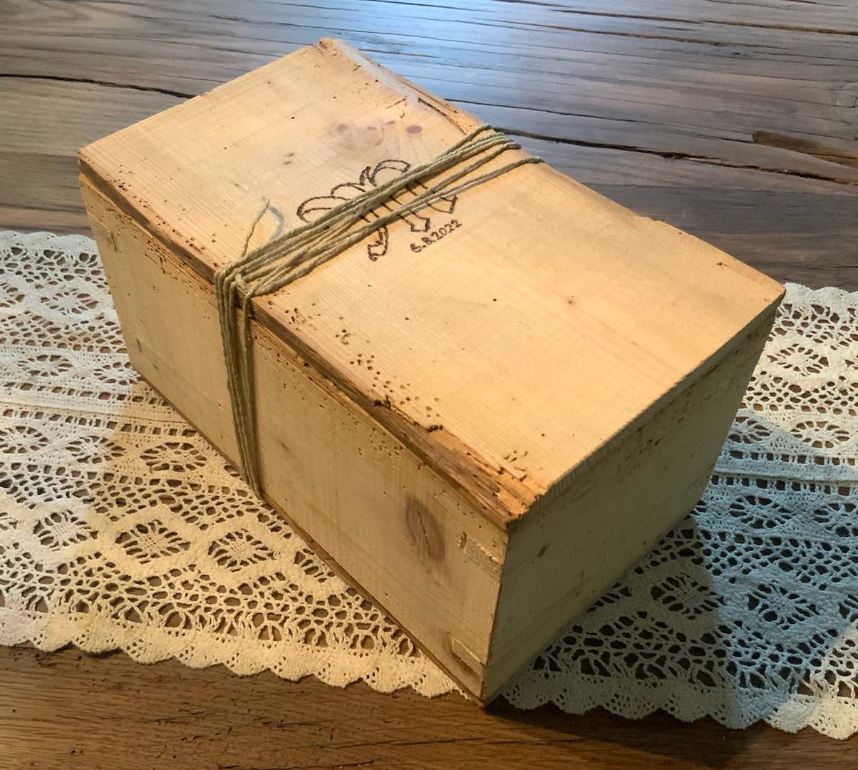 Verschnürte Geschenkbox mit gebrannter Initiale aus altem Fichtenholz mit Gin auf Holztisch