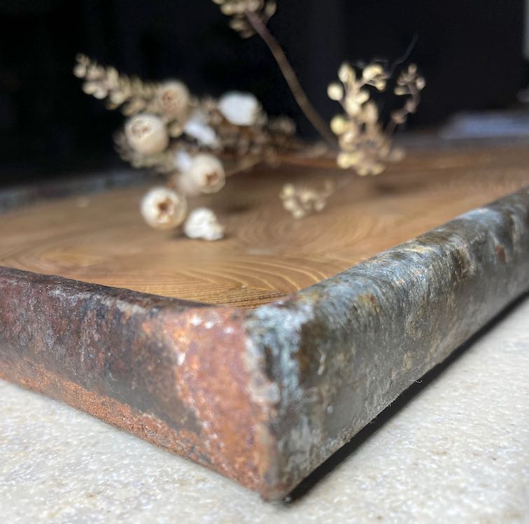 Close-up Tablett aus Robinien-Stirnholz und Rahmen aus rostigem Metall mit Deko auf Steinplatte