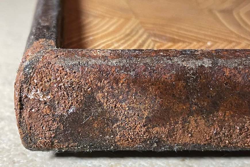 Close-up Tablett aus Robinien-Stirnholz und Rahmen aus altem rostigem Metall auf Steinplatte