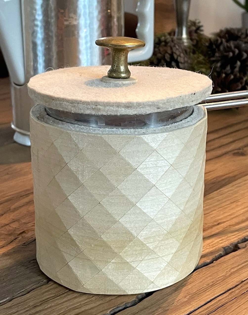 Kännchen in Holz-Textil mit Filzdeckel und altem Messingknopf auf Holztisch