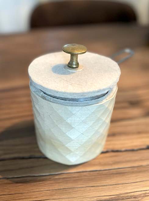 Kännchen in Holz-Textil mit Filzdeckel und altem Messingknopf auf Holztisch