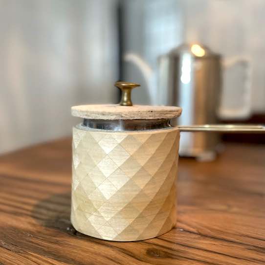 Kännchen mit Holz ummantelt und mit Filzdeckel und altem Messingknopf auf Holztisch