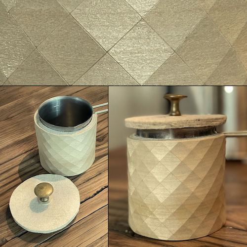 Mit Filz und Holz-Textil isoliertes Milchkännchen mit Deckel auf Altholz-Platte