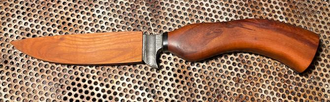 Damastmesser mit Kirschholz-Griff in Scheide aus Holz auf Lochblech