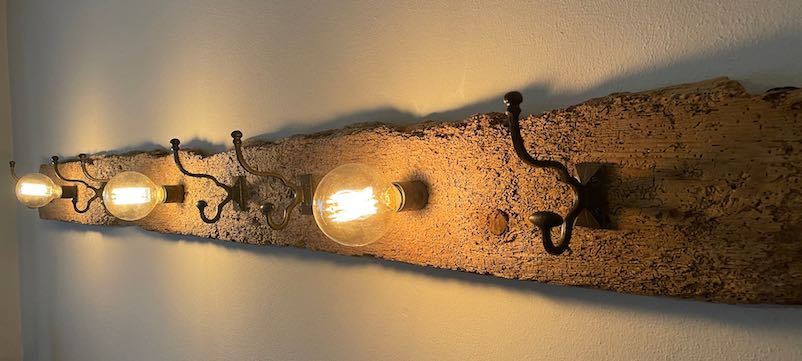 Garderobe aus wurmstichigem Holz mit gusseisernen Haken und Vintage Glühbirnen
