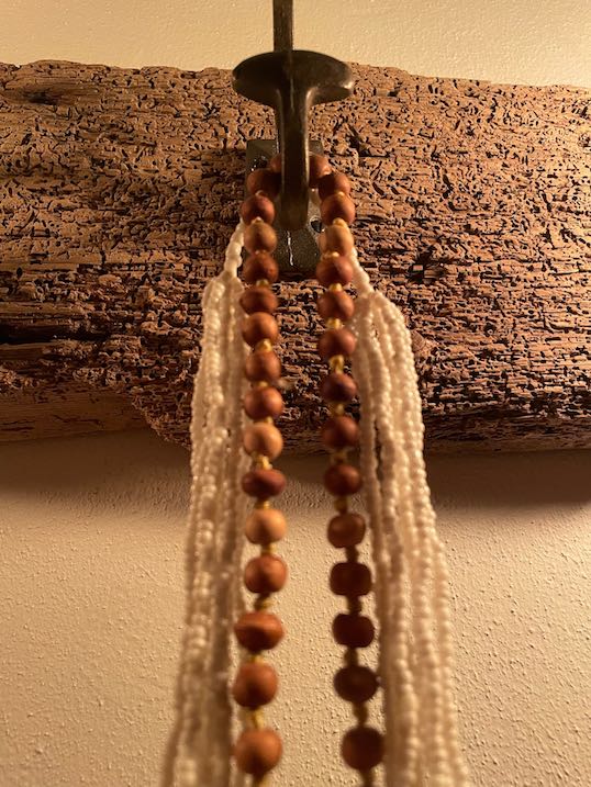 Gusseisener Garderobenhaken auf wurmstichigem Brett mit Schmuck