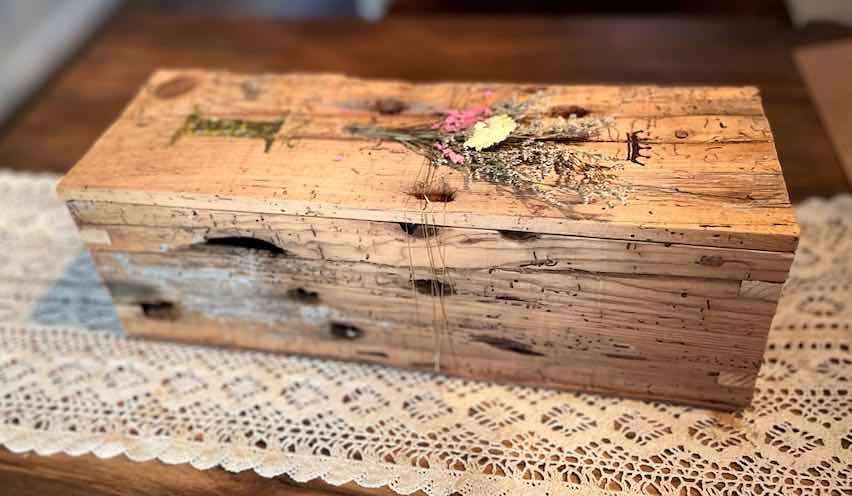 Geschenkbox aus altem Holz mit Trockenblumen auf Tisch