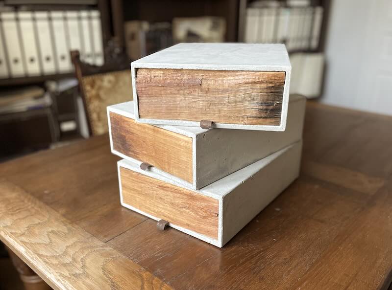 3 gestapelte Boxen aus Beton mit Holzschubladen und Altholzfront auf Schreibtisch